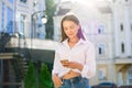 A young, fashionably dressed girl with a smartphone on a city st