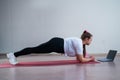 Young fat caucasian woman doing a plank on a sports mat. A cute plus size girl in sportswear is doing fitness exercises Royalty Free Stock Photo