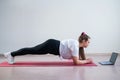 Young fat caucasian woman doing a plank on a sports mat. A cute plus size girl in sportswear is doing fitness exercises Royalty Free Stock Photo