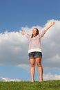 Young fat girl stands at grass, raises her hands