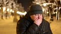 Young fat man feels nauseous and closes his mouth in winter time