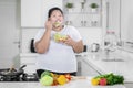 Young fat woman eats tasty salad in kitchen Royalty Free Stock Photo