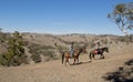 Young father as horse instructor of young teen daughter riding little pony wearing cowgirl hat