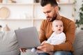 Young Father With Baby Working On Laptop Sitting At Home Royalty Free Stock Photo