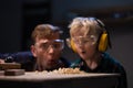 A young father and a blond son blow sawdust off a carpenter`s table after work. Royalty Free Stock Photo