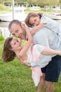 Young father carrying one daughter on his back and another girl child in front piggyback Royalty Free Stock Photo