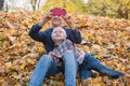 Young father and cute child sitting in autumn Park on fallen leaves. Dad and boy make pictures for phone