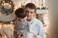 Young father dad holding on hands cute little boy son and cup of hot cacao or tea, happy small child toddler enjoying time with