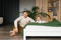 Young father is hanging near the bed on which his baby son is lying Royalty Free Stock Photo