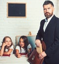 Young father helping his daughters with school project at home. man put book in bag. Royalty Free Stock Photo