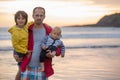 Young father with his beautiful children, enjoying the sunset over the ocean on a low tide in Devon Royalty Free Stock Photo