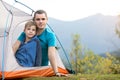 Young father with his child son resting together in a hiker tent in summer mountains. Active family recreation concept