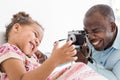 Young father with his cute little daughter taking pictures of each other on an old vintage camera Royalty Free Stock Photo