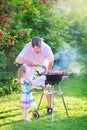 Young father and his daughter grilling in the garden Royalty Free Stock Photo