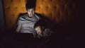 Young father and his little son watching cartoon movie using tablet computer and talking while lying in bed in evening Royalty Free Stock Photo