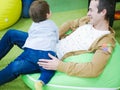 Young father with his son in the playroom. Happy young father plays with his cute little smiling son in a playroom on balloons and