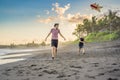 Young father and his son running with kite on the beach Royalty Free Stock Photo