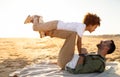 Young father and his son sharing a special moment on the coastline, man lying on plaid and raising the boy on his feet Royalty Free Stock Photo