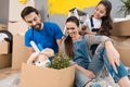 Young father and his wife and daughter sort things out from cardboard boxes in house they moved.