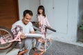 Young father holding bicycle frame and daughter carrying wheels Royalty Free Stock Photo