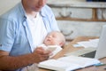 Young father holding newborn child and using mobile phone Royalty Free Stock Photo