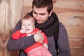 Young father holding son against wooden background