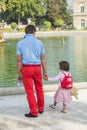 Young father holds daughter's hand in Luxembourg Garden, Paris