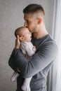 A young father holds his little son in his arms and kisses him, the baby yawns Royalty Free Stock Photo