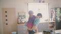 Young father is jumping around the house with his cute little daughter on his back. Slow mo, Steadicam shot