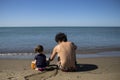 Young father and little daughter sitting on the beach and playing with sand Royalty Free Stock Photo