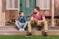 Young father with little son sitting on porch at backyard Royalty Free Stock Photo
