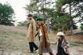Young father, mother and little toddler daughter girl in a beret and a coat walk holding hands in the autumn forest. Royalty Free Stock Photo