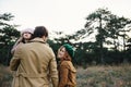 Young father, mother and little toddler daughter girl in a beret and a coat walk holding hands in the autumn forest. Royalty Free Stock Photo