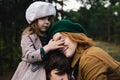 Young father, mother and little toddler daughter girl in a beret and a coat walk holding hands in the autumn forest. Royalty Free Stock Photo