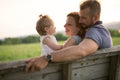 Young father and mother with their cute daughter sit on a bench at the sunset Royalty Free Stock Photo