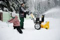 Young father operates snow blower Royalty Free Stock Photo