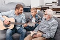 Young father playing guitar while little son and grandfather are Royalty Free Stock Photo