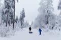 Young father pull little toddler girl and school kid boy on snow tube. Happy children having fun outdoors in winter on