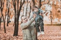 A young father raises a child in his arms in an autumn park Royalty Free Stock Photo