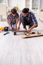 Young father repairing skateboard with his son at home