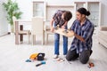 Young father repairing skateboard with his son at home