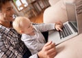 Showing dad how its done. A young father showing his baby girl how to use a laptop.