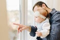 Young caucasian father showing his baby girl something in the window