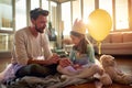 A young father sits on the floor with his little daughter at home and preparing for ballet practice. Family, together, home