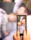 Young father sleeping with cute sleeping newborn baby lying on his chest with arms down. Mother is documenting the scene with a sm Royalty Free Stock Photo