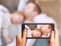 Young father sleeping with cute sleeping newborn baby lying on his chest with arms down. Mother is documenting the scene with a sm Royalty Free Stock Photo