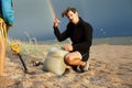 Young father with son on beach digging pit under the rainbow, playing, looking for treasure, lifestyle happy family on