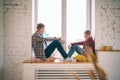 Young father with a son, a boy of 8 years old, sitting on the windowsill and looking out the window, time together, family Royalty Free Stock Photo