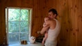 Young father stands in kitchen and keeps baby. Dad cradles and soothing baby