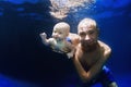 Young father swimming underwater with baby son in the blue pool Royalty Free Stock Photo